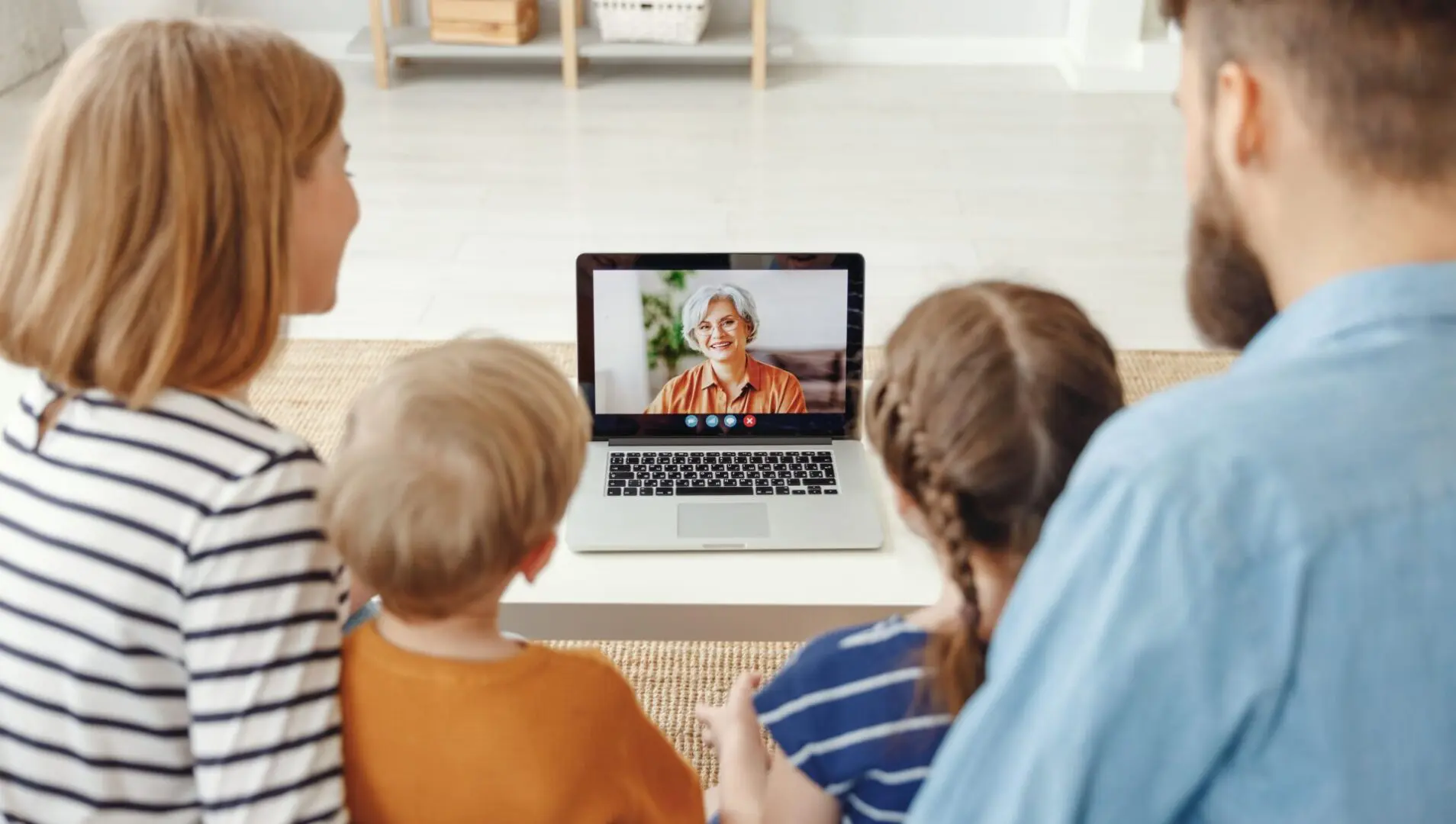 Family video chatting with elderly woman online.
