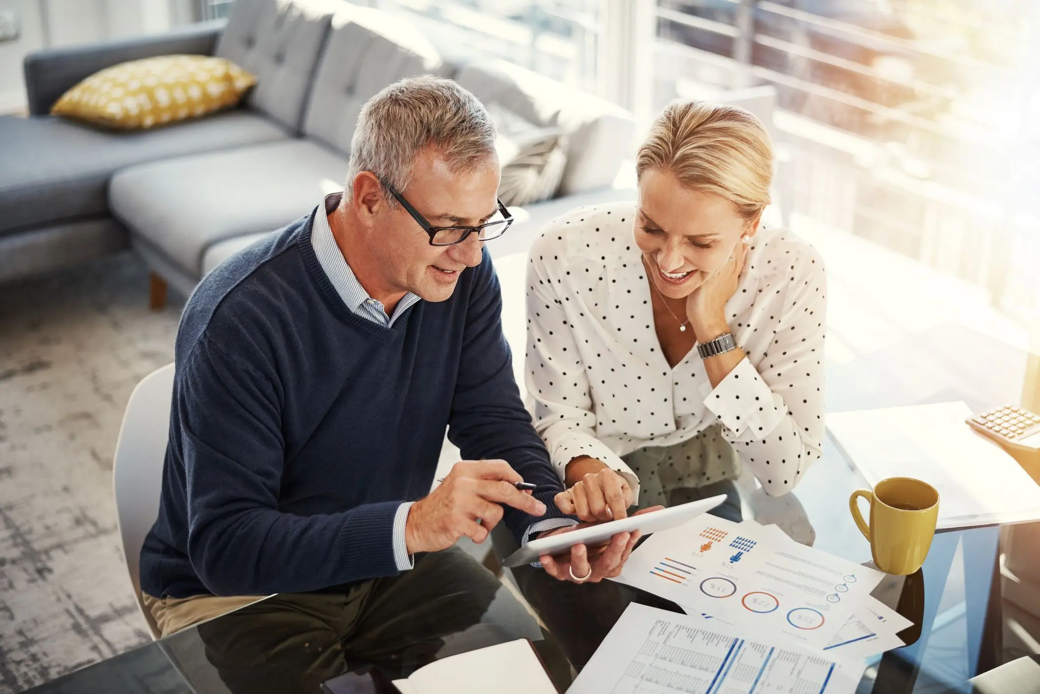 Man and woman reviewing documents and tablet.